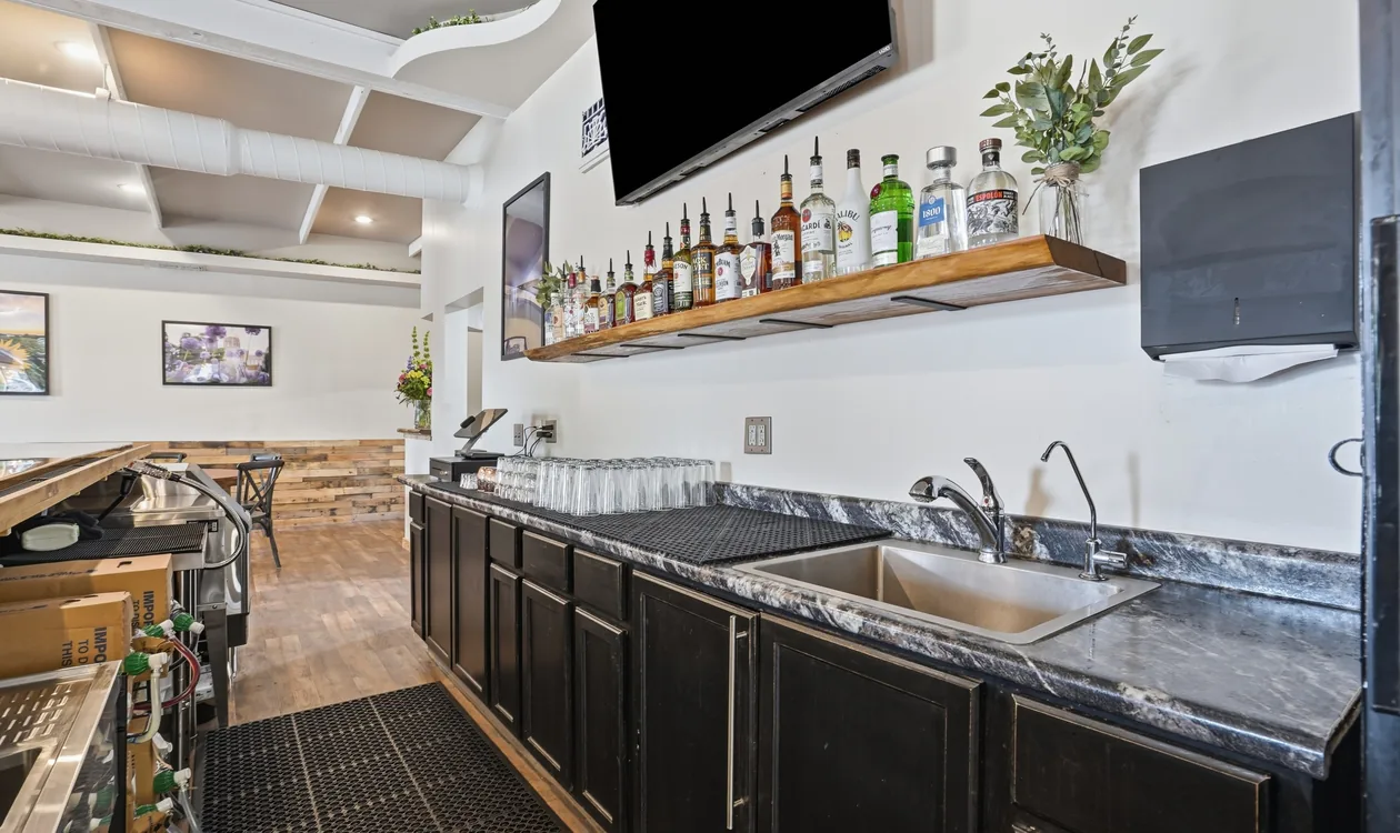 The back bar at Venue 209 with a floating shelf of spirits, a sink and stocked glassware
