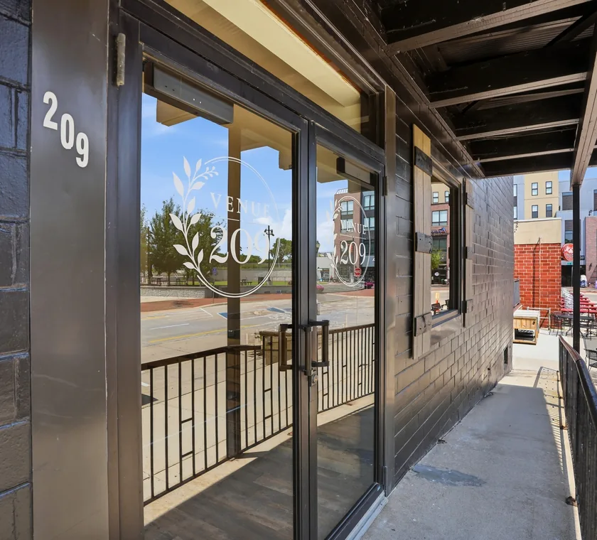 Etched glass entrance doors carrying the Venue 209 wreath mark, opening onto State Street