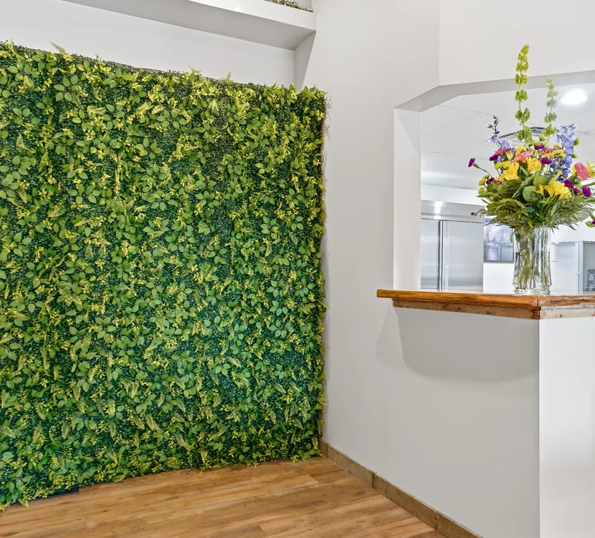 The greenery living wall at Venue 209 beside the kitchen pass-through window with fresh flowers