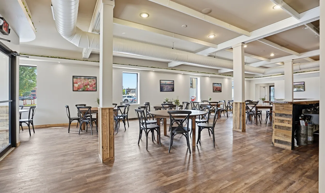 Round wood tables and black cross-back chairs set for a seated dinner at Venue 209