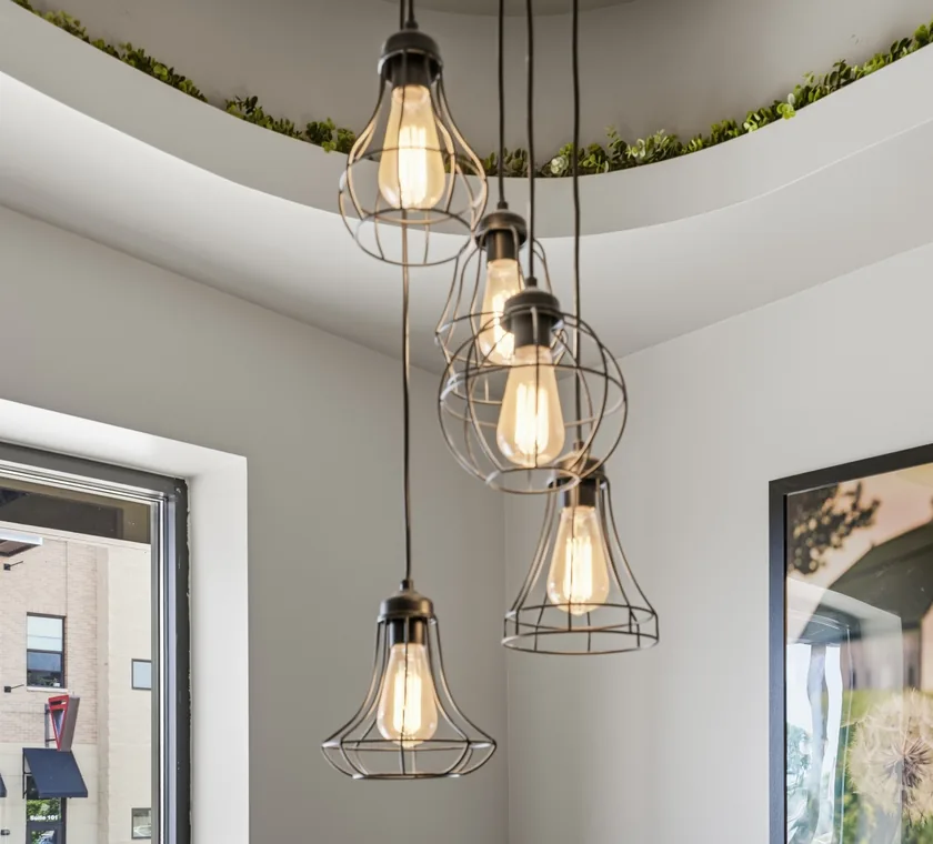 Caged Edison pendant lights hanging beside a curved soffit trimmed with greenery
