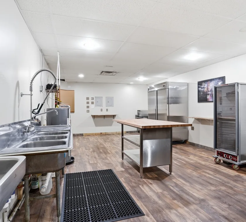 The prep kitchen at Venue 209 with a three-compartment sink, butcher block prep table, reach-in refrigeration and a warming cabinet