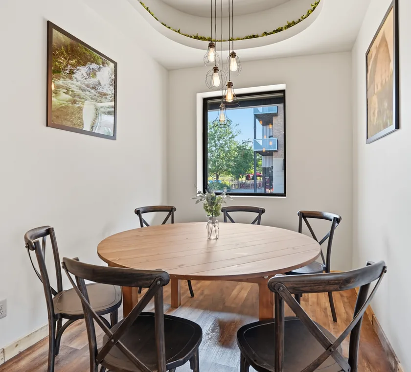 A private round table for six beneath a cluster of caged Edison pendant lights