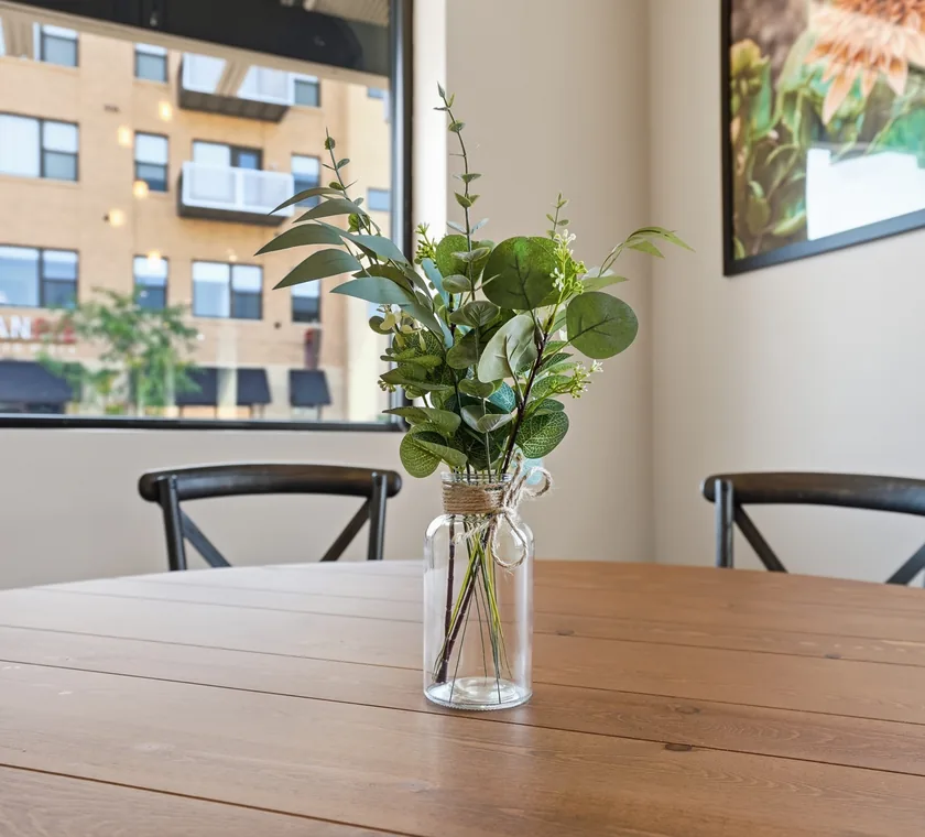 A eucalyptus and greenery centerpiece in a glass jar on a solid wood table